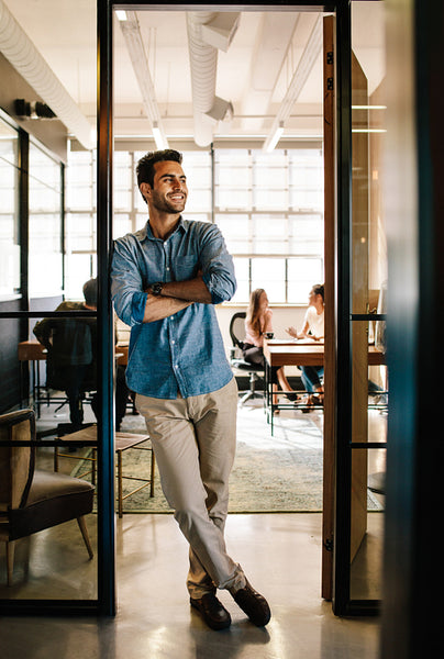 Happy young man standing in office doorway