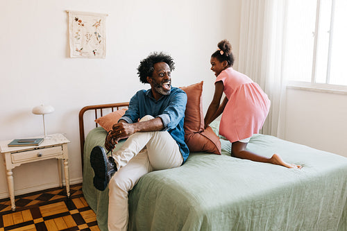 Black girl playing with her dad as he prepares for work
