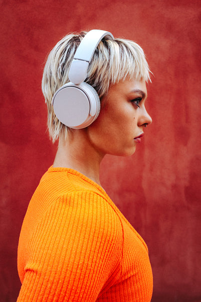 Blonde woman wears headphones in side profile against a red background