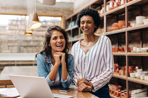 Successful shop owners smiling at the camera in their ceramic store