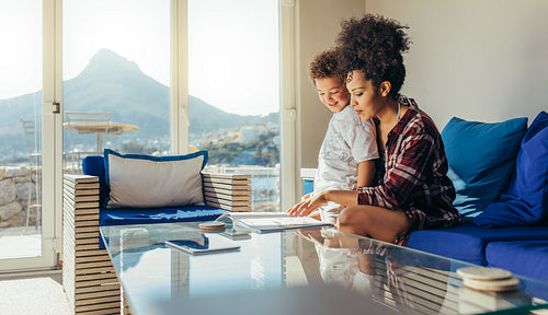Mother and child sitting together in living room and studying
