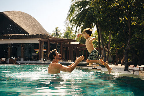 Father and young boy enjoying a playful time in resort pool