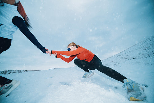 On a snowy hill, women are running through winter training together