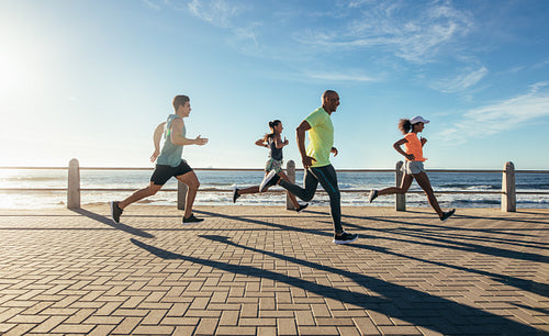Young people running along seaside