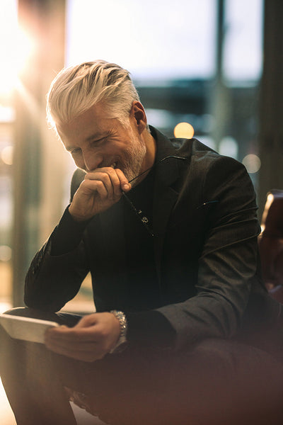 Mature businessman using phone in office lobby