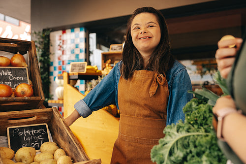 Happy woman with Down syndrome assisting a customer in a grocery store