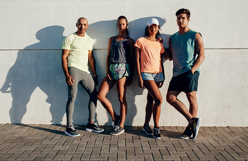 Young runners standing together by a wall
