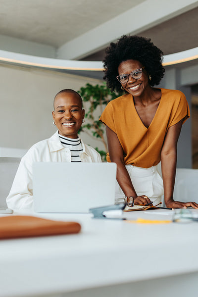 Two business women collaborating on a creative design project in a professional office