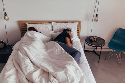 Couple sleeping back on back in bed
