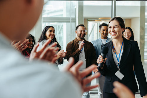 Female leader receives applause in a successful business meeting, showcasing effective leadership and teamwork in a corporate environment.