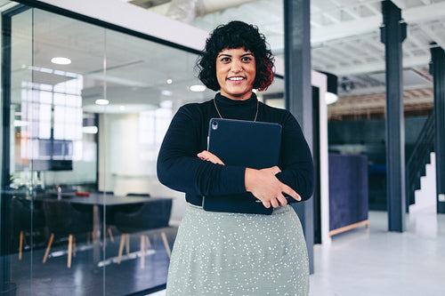 Businesswoman holding a touchpad while standing in a creative office