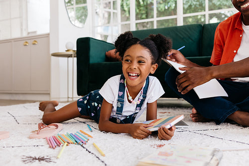 Young daughter enjoying a creative drawing session with father at home