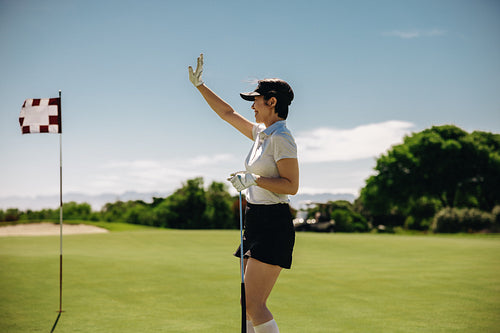 Sportswoman in golf attire waves on the putting green during a match