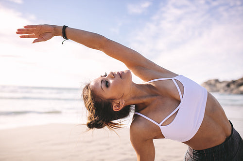 Fitness females doing side stretches at beach