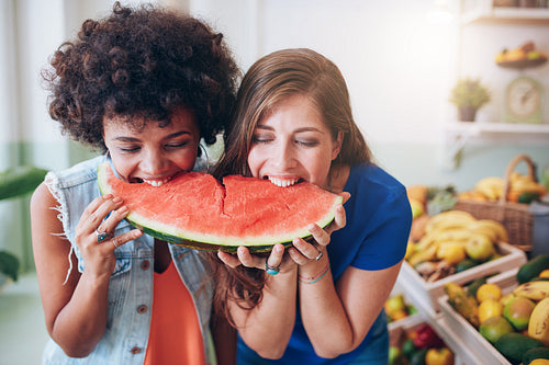Two young woman eating watermelon and having fun