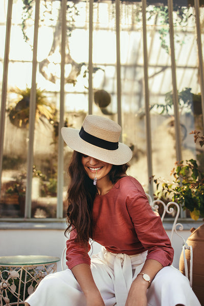 Happy young tourist woman wearing a summer hat outside a hotel