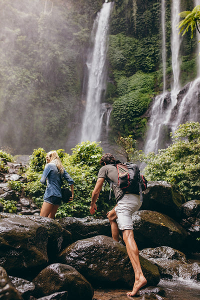 Couple crossing a stream together in the forest