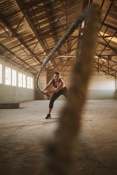 Fitness woman exercising with battle rope