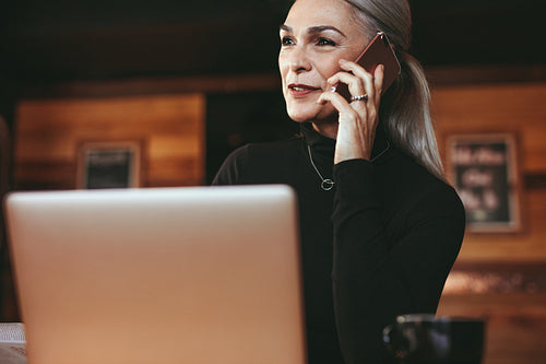 Senior woman sitting at coffee shop talking on phone
