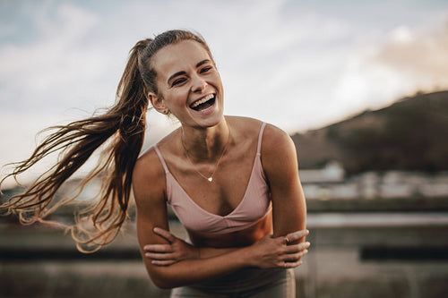 Laughing female runner standing outdoors