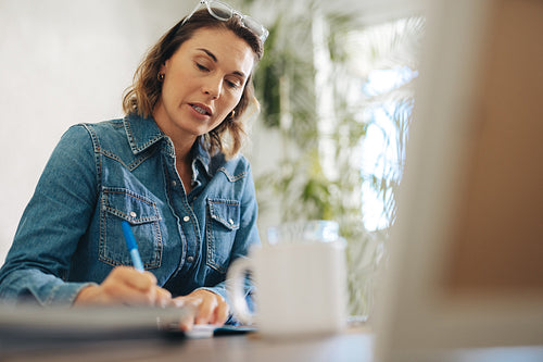 Businesswoman writing during a virtual meeting