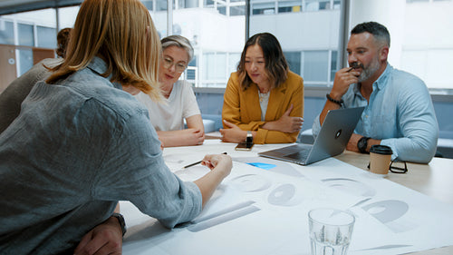 Creative business people discussing architectural drawings and blueprints in a meeting