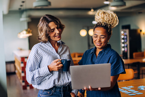 Two women discussing work while looking at a laptop in a casual setting