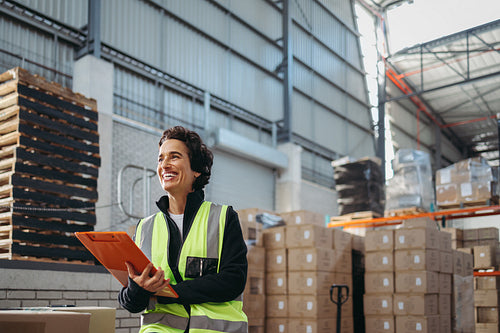 Mature warehouse manager smiling while holding a file