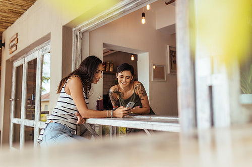 Two friends looking at mobile phone sitting at table