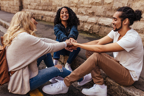 Group of friends sitting together stacking their hands on one another