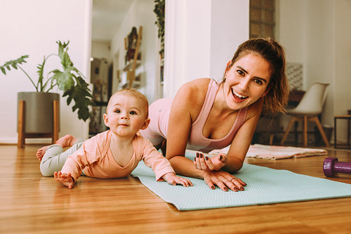 Cheerful mom doing plan exercises with her baby at home