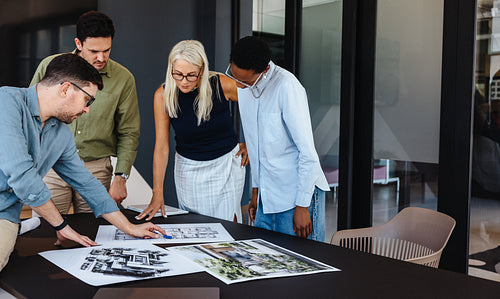 Group of diverse professionals discussing blueprints in a modern workspace