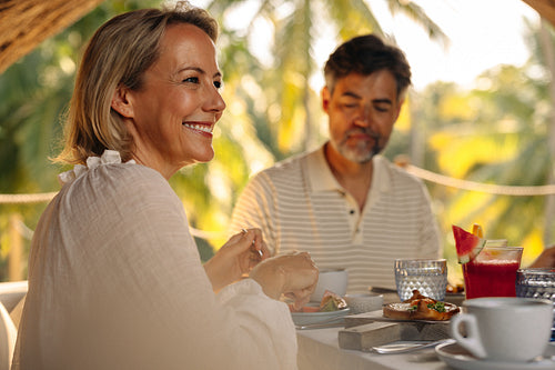 Happy woman enjoying tropical vacation breakfast with companion