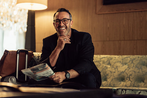 Happy mature businessman waiting in hotel lobby
