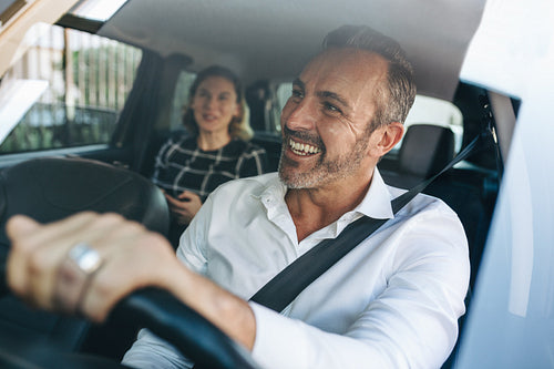 Taxi driver talking to a female passenger in car