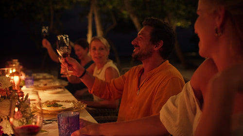 Happy friends and family enjoy a special evening dinner at a beautiful island resort