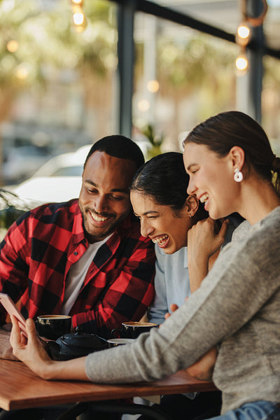 Group of friends sitting at cafe using a phone