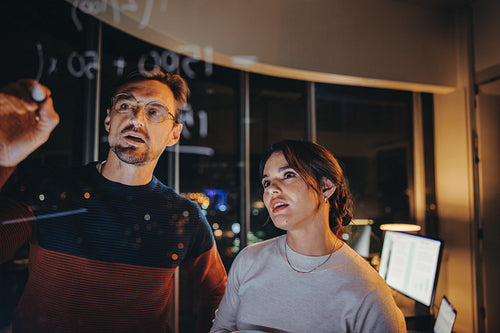 Business team having a late night brainstorming session in a glass walled office