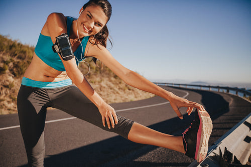 Young woman stretching on guardrail outdoors
