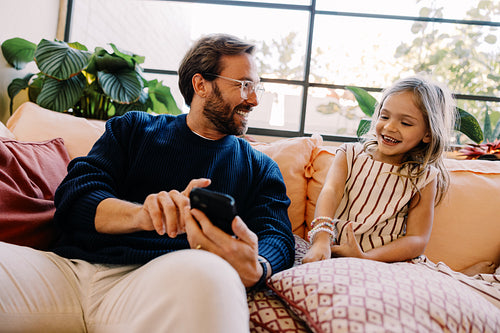 Family moment: dad and daughter on couch with phone