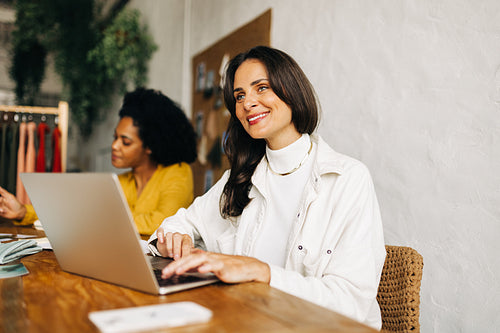 Business woman using a laptop to create fashion designs for her clothing store