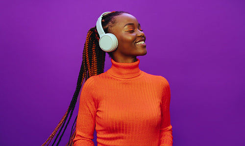 Colorful background with happy woman listening to music on headphones