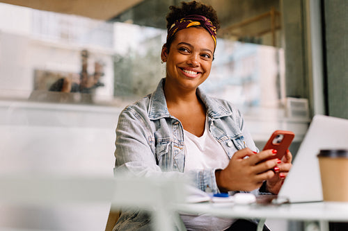 Young woman enjoying coffee break at a cafe, using phone