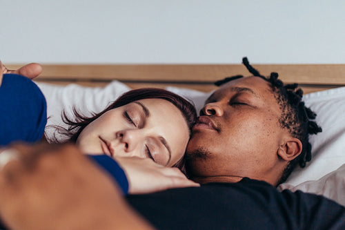 Mixed race couple sleeping together in bed
