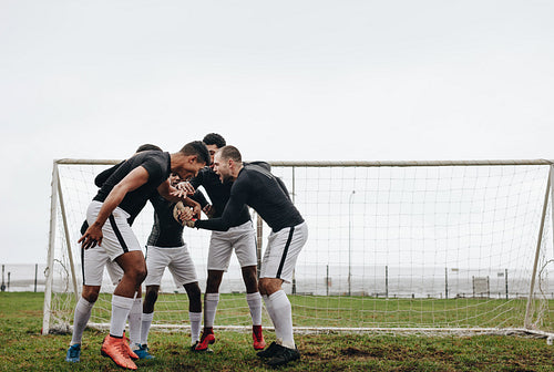 Football players standing in a huddle near goalpost
