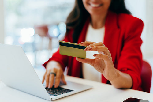 Woman holding credit card while using laptop for online transaction