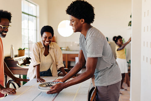 Family breakfast at home: Parents and son setting the table in the kitchen