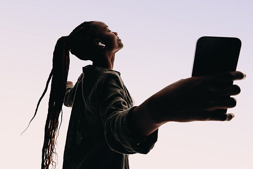 Silhouetted woman dancing and listening to music on her phone in a studio