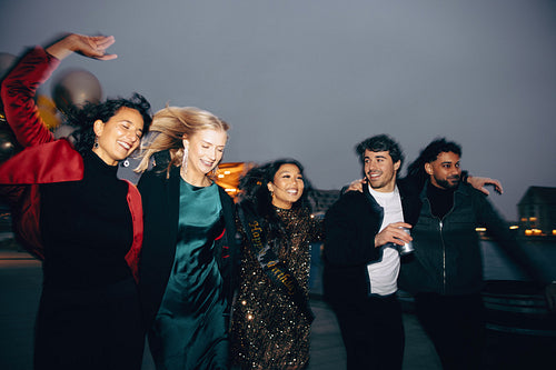 Group of friends dancing together outside during an evening celebration