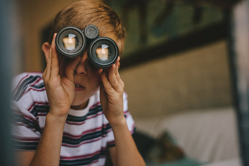 Boy looking through binoculars from the living room